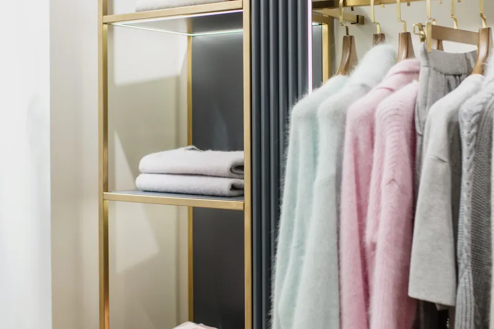Folded towels on open shelves beside clothes on hangers