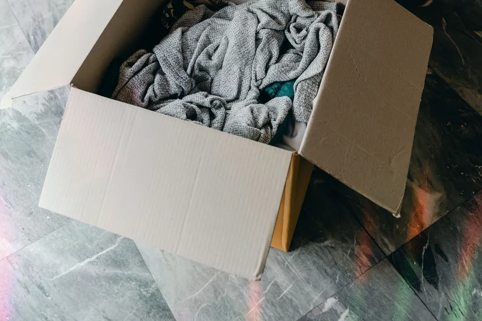Open and closed cardboard boxes holding belongings on a room floor